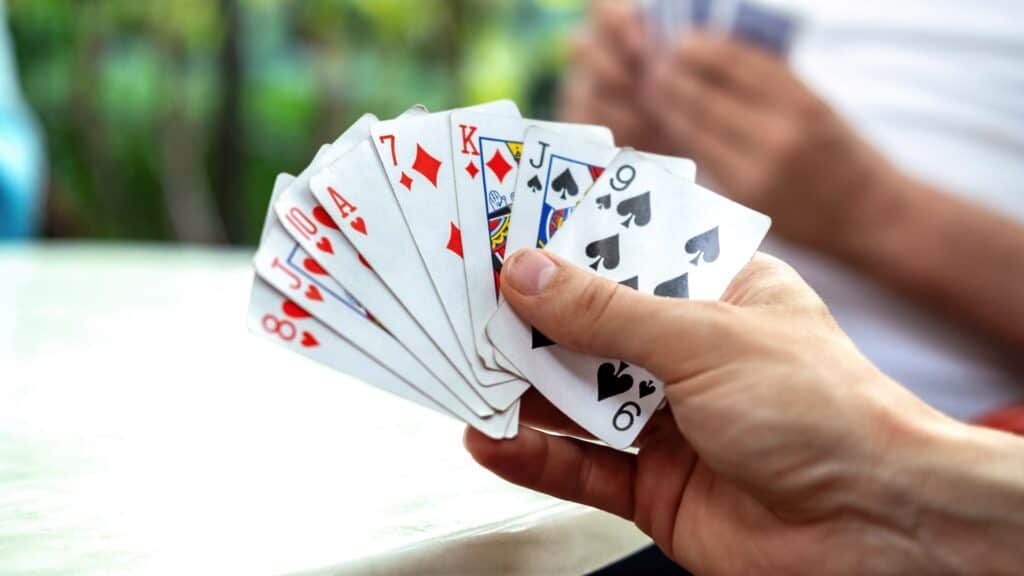Person hält ein Kartenspiel im Freien, Fokus auf die Karten.
